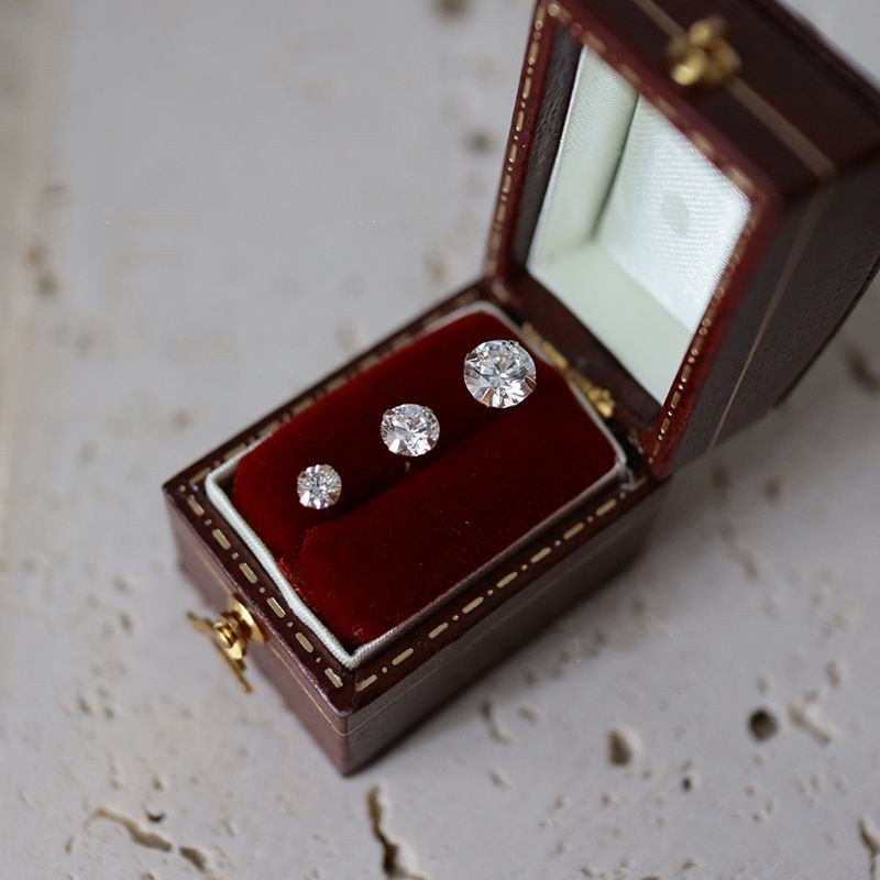 Three pairs of 14ct solid gold zircon stud earrings in 3 mm, 4 mm and 5 mm sizes, showing the sizes in a gift box on a neutral stone surface.