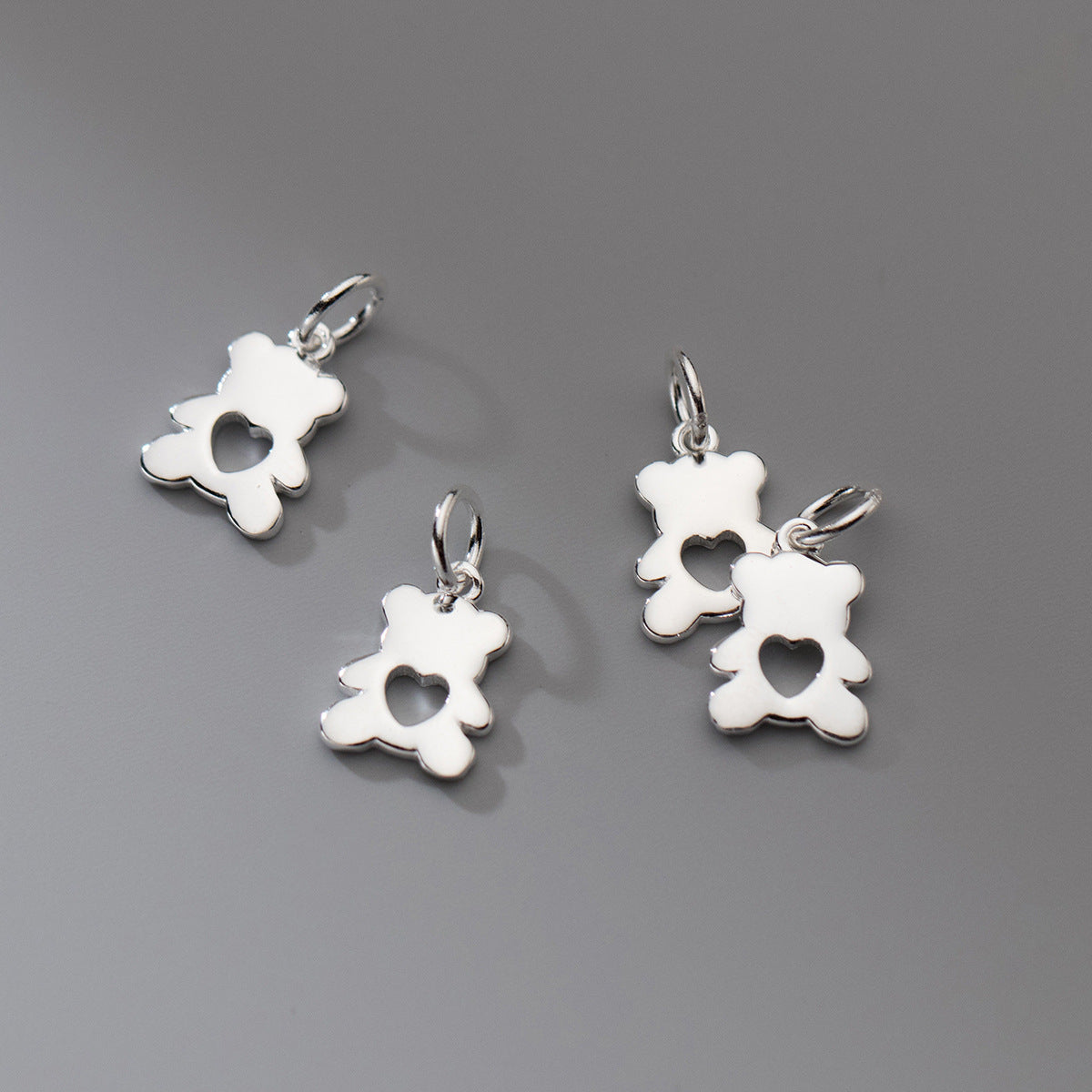 Four silver bear-shaped pendants on a gray background