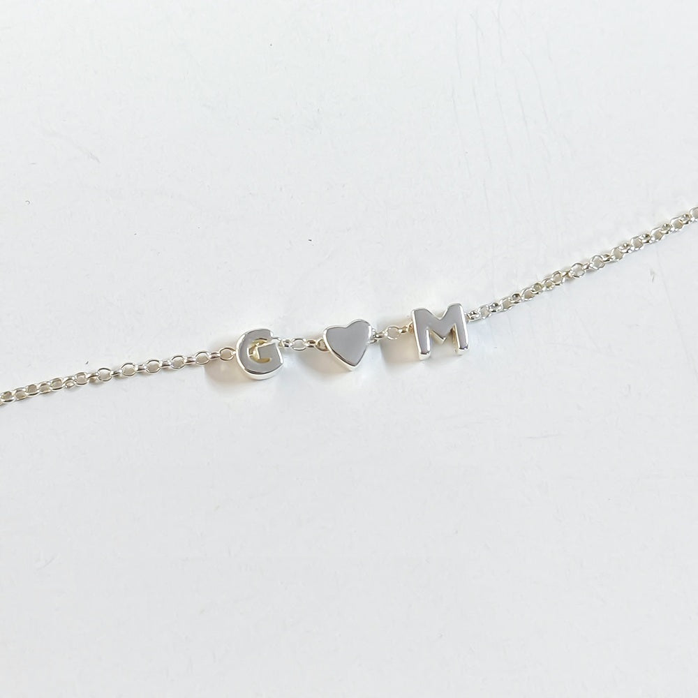 925 sterling silver bracelet with slider letter charms G heart charm M on a light gray background