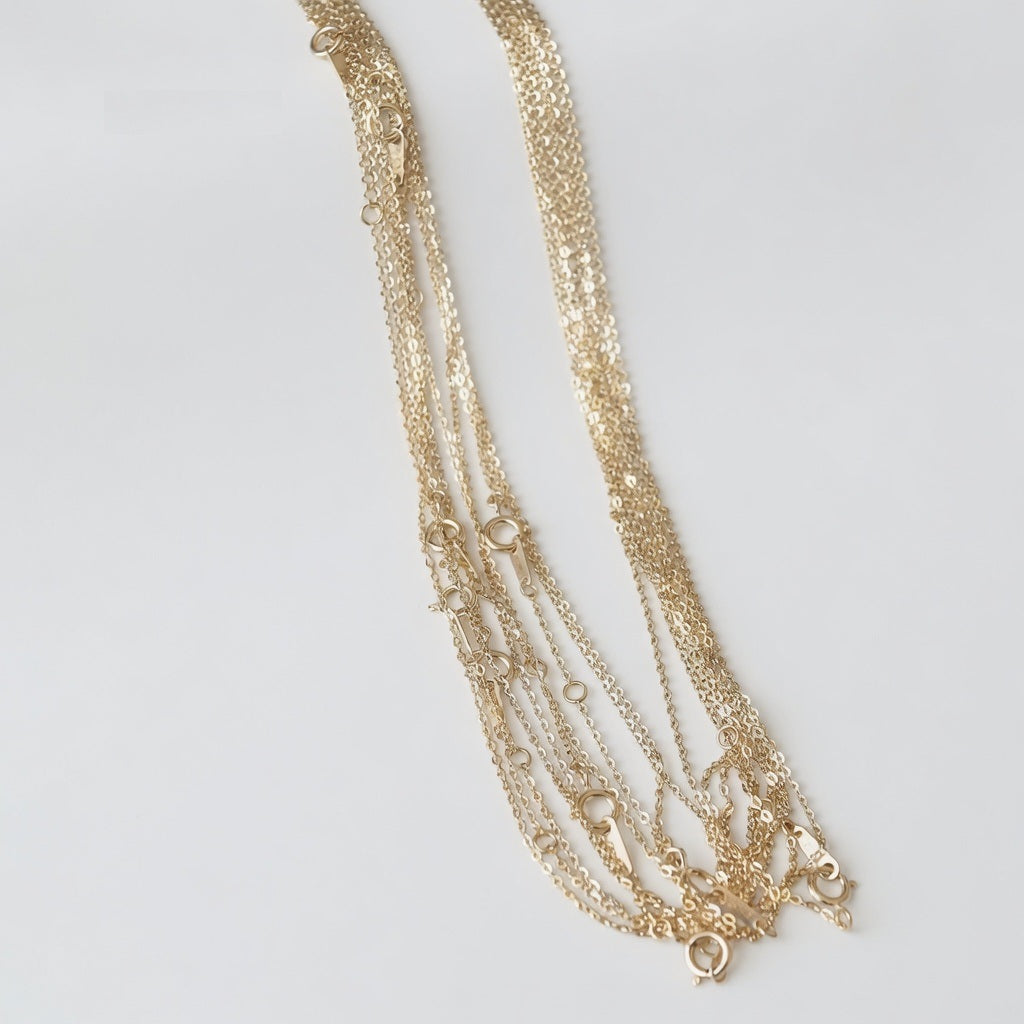 14ct solid gold cable chain necklaces on a light background