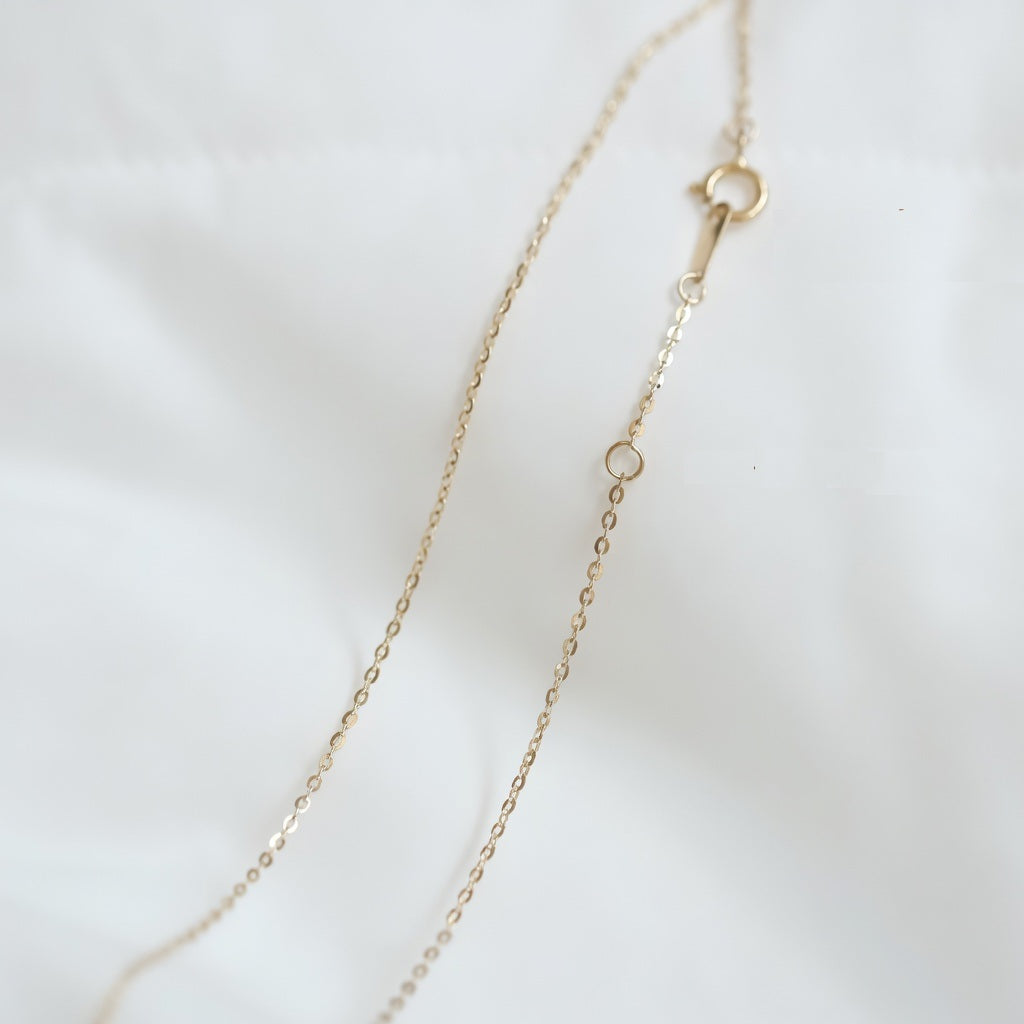 14ct solid gold cable chain necklace closed up showing spring ring clasp on a light background
