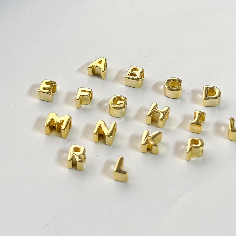 Gold letter beads on a white background