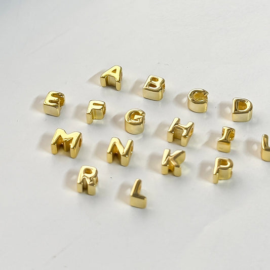 Gold letter beads on a white background