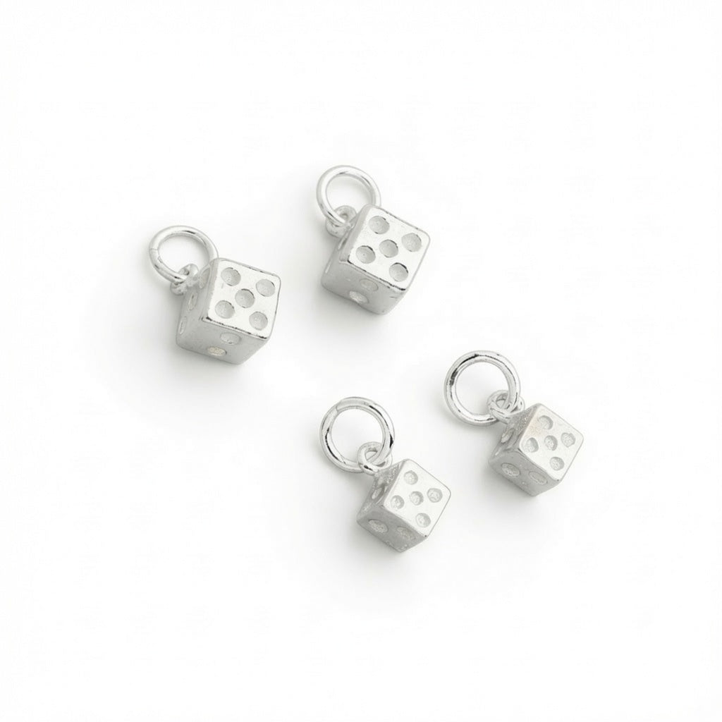 Four 925 sterling silver dice charms 6.5 mm and 5 mm with attached jump rings, arranged on a plain white background.