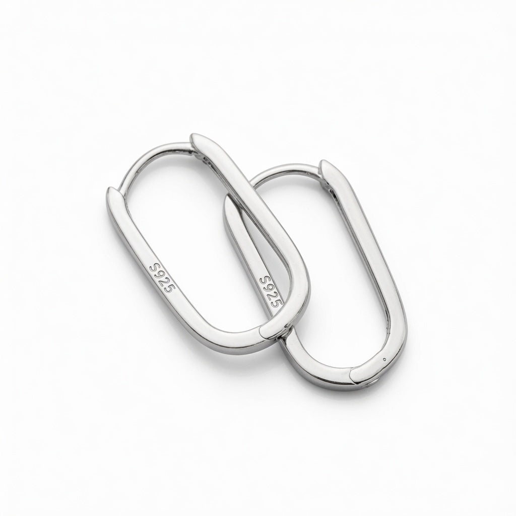 Close-up of two sterling silver oval hoop earrings on a white background, showing the S925 hallmark and hinged closure detail