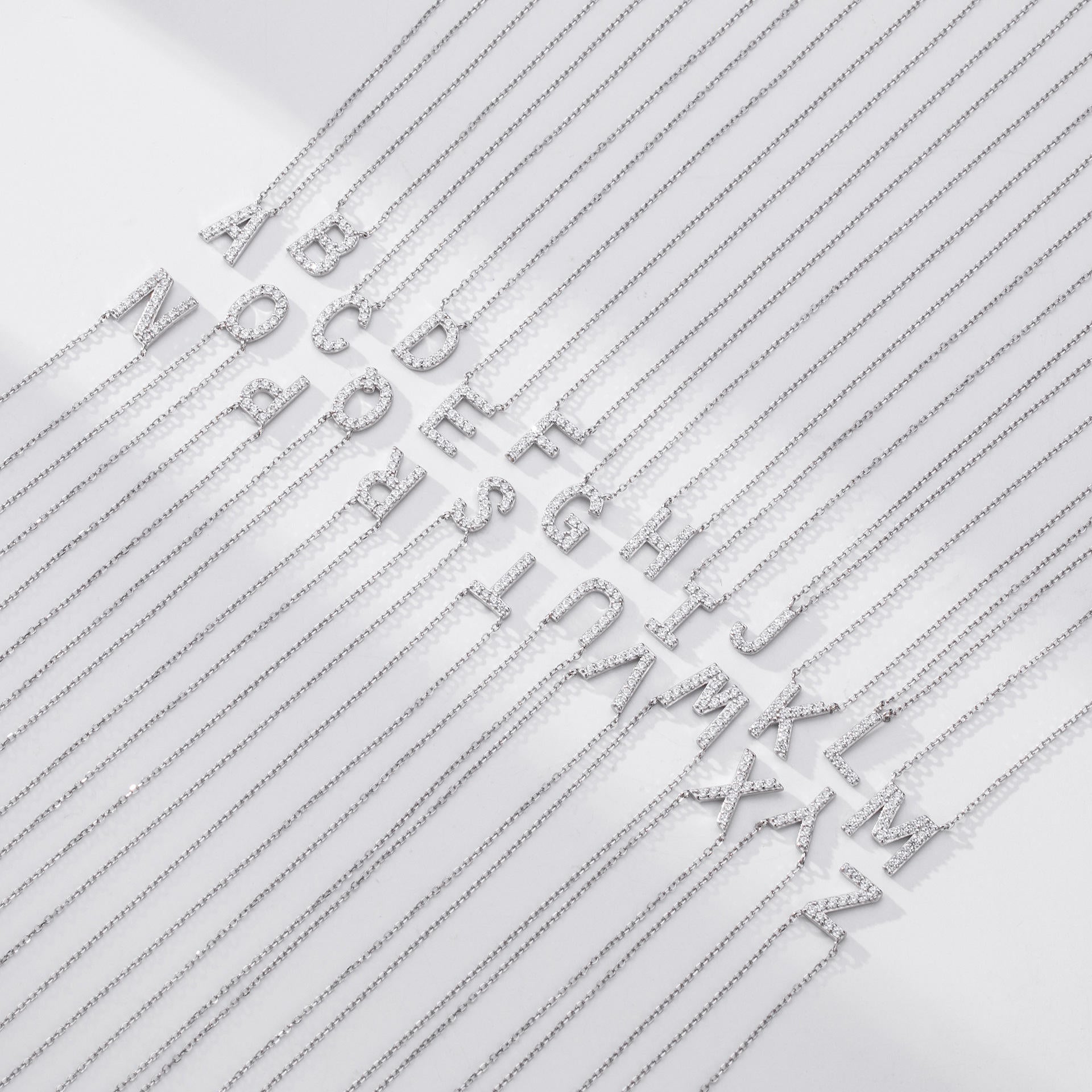 Silver letter necklaces with chain links on a light gray background
