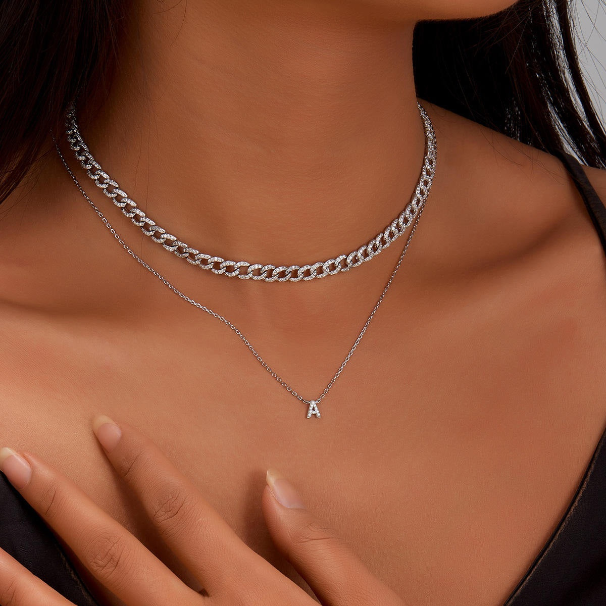 Silver chain necklace and crystal letter A pendant on a woman's neck with a blurred background