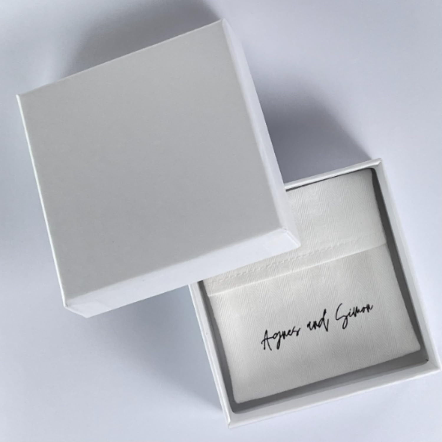 White jewelry box with 'Agnes and Simon' branding on a light gray background