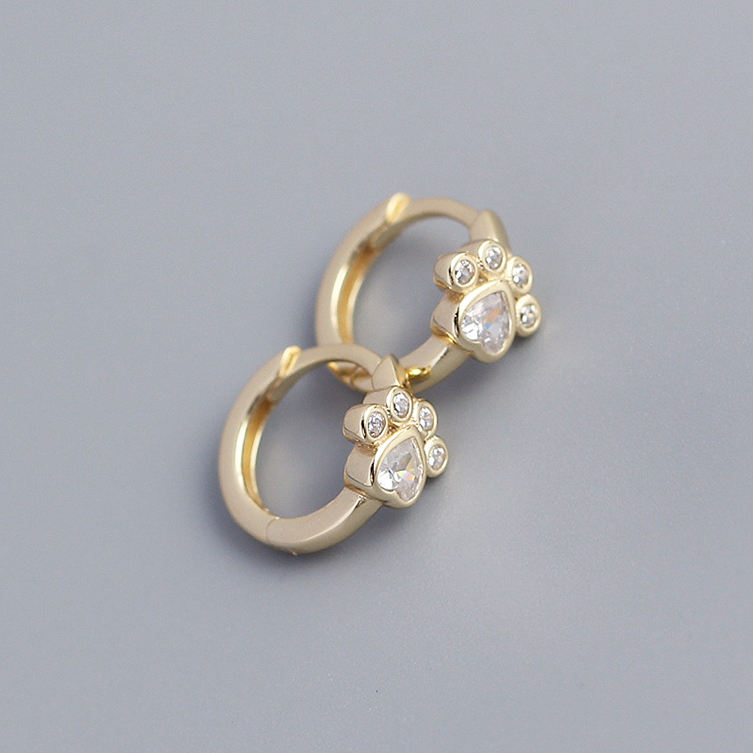 Gold hoop earrings with clear crystal gemstones on a gray background